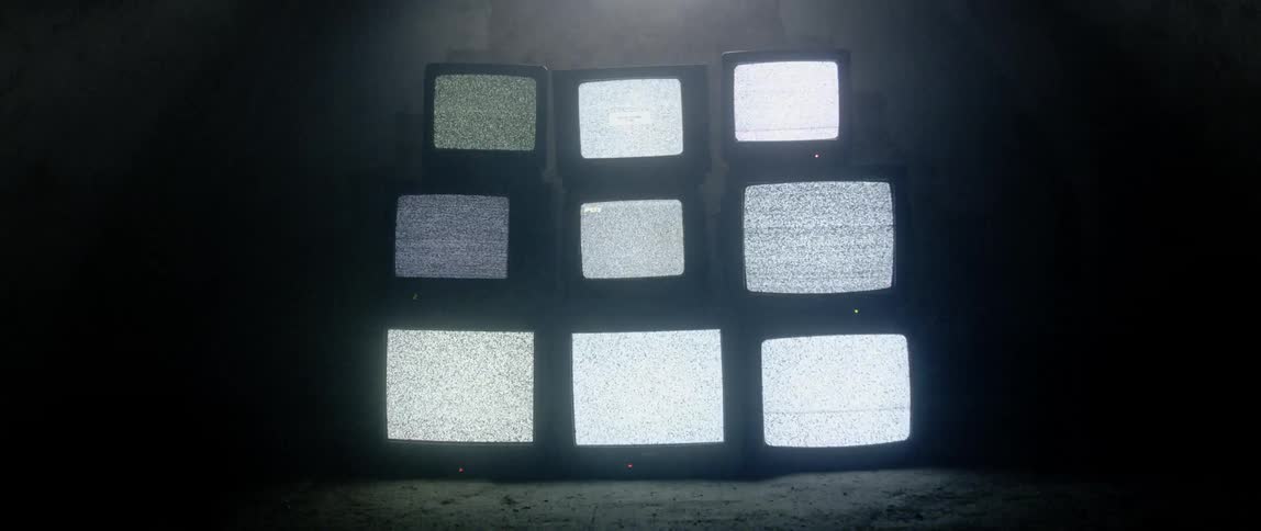 Static plays on the screen of nine tube televisions stacked in a three by three format