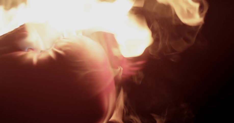 A person with boxing gloves on punches while surrounded by flames