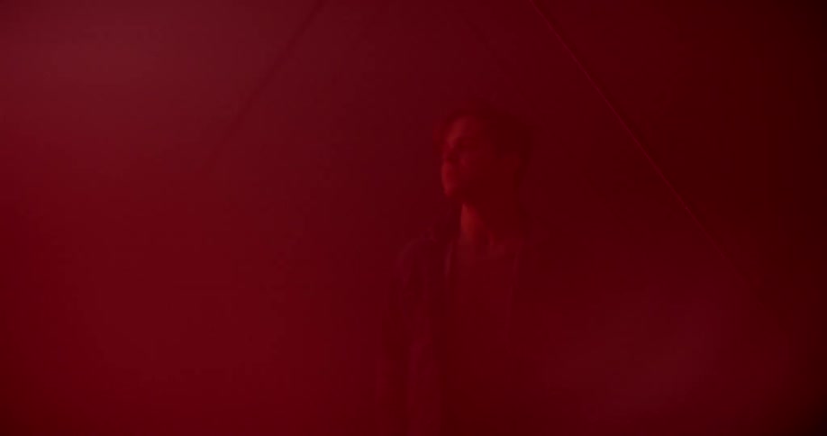 A man walks into a room with triangle lights and colored lights flashing around him