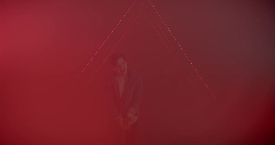A young man sings on a smokey stage with lights flashing