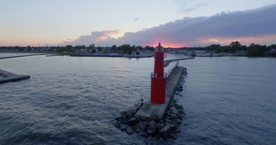 A lighthouse on a cement slab with the shoreline behind it