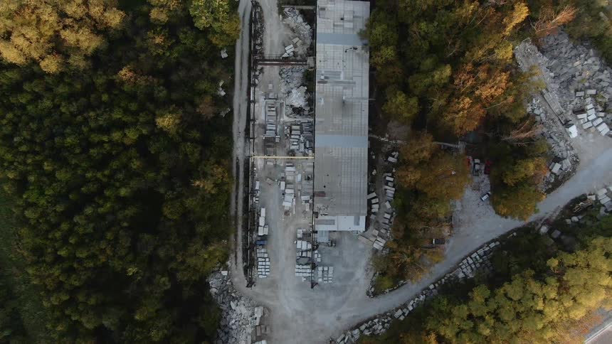 A large building and parking lot are surrounded by trees and shown from above