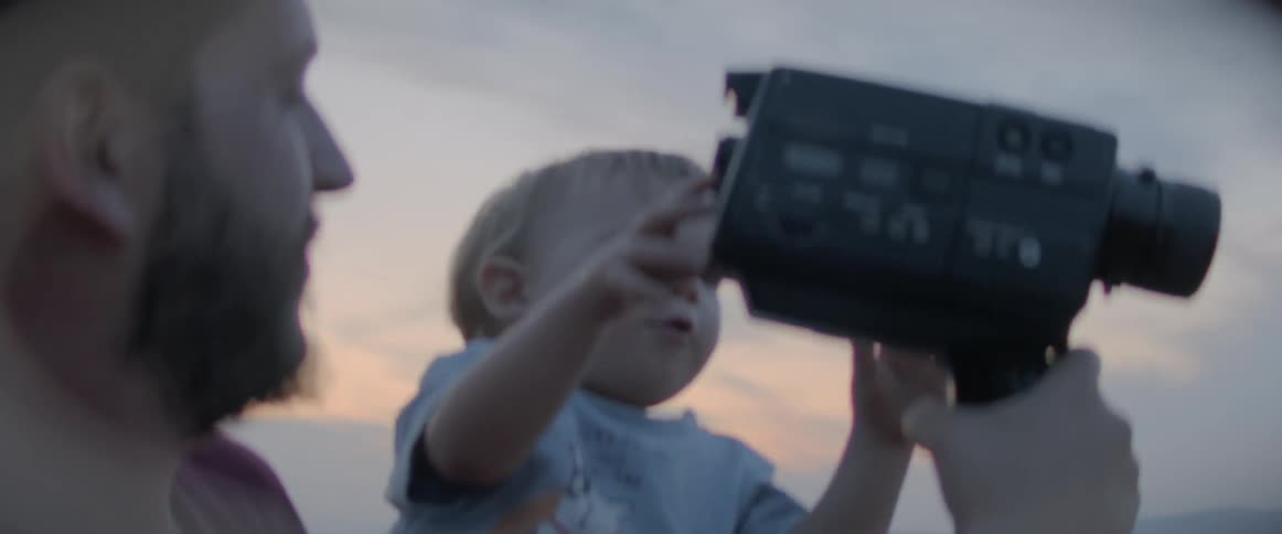 Father and son are playing with a camera outdoors