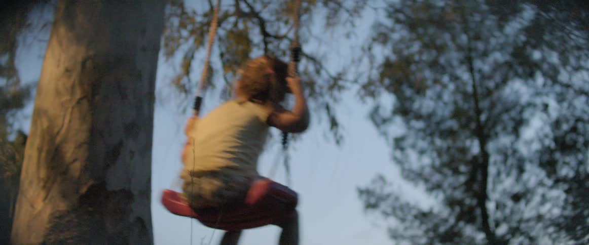 A young child swings on a tree swing