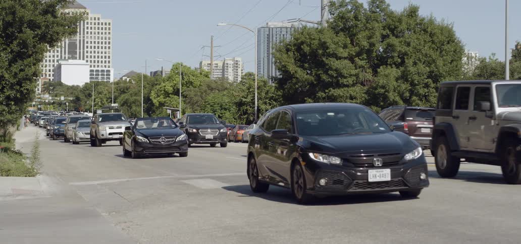 Several cars drive slowly through an intersection in an urban area