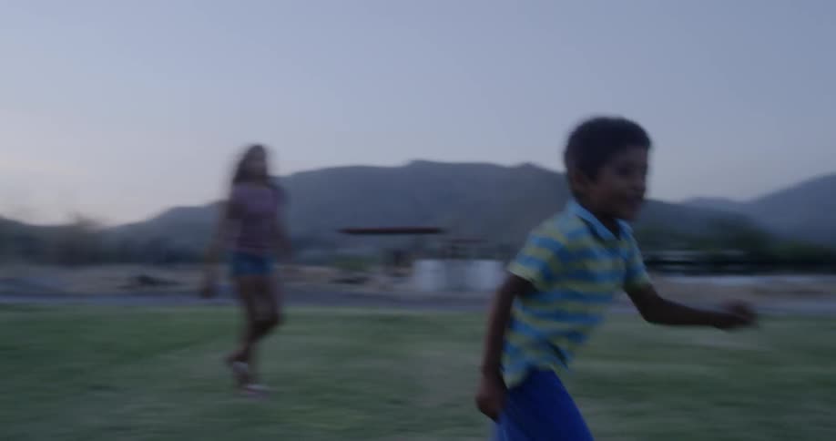 A little boy plays outside and kicks a ball