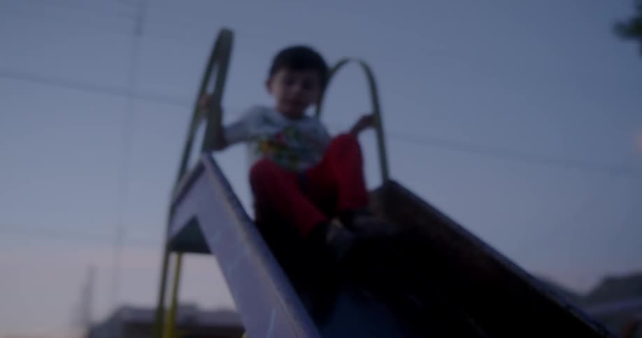 A young child slides down a playground slide
