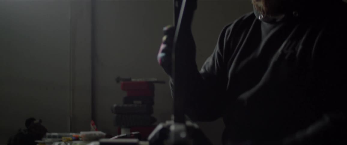 Man picks up a piece of metal and places it in a vise in his workshop