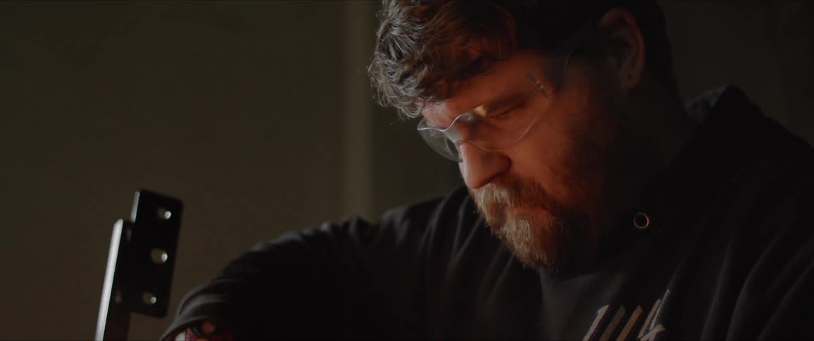 A man is creating sparks as he grinds metal in a workshop