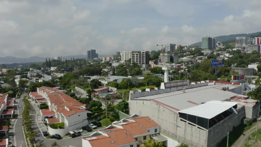 A city on a hill with lots of trees and mountains in the background in the daytime