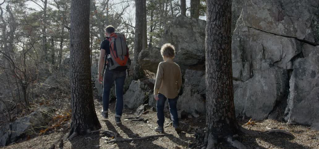 Father and son hiking on a trail through the forest