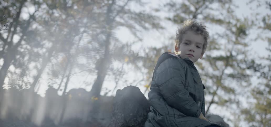 A young boy sits on a rock