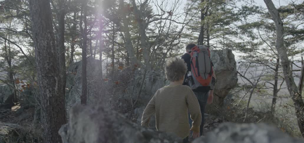 A man and child hike over rocks
