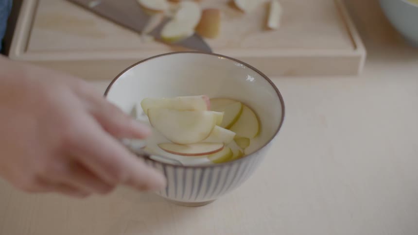 Woman places a spoon in a bowl of fruit