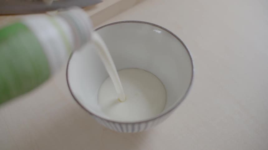 Yogurt being poured in bowl on kitchen top