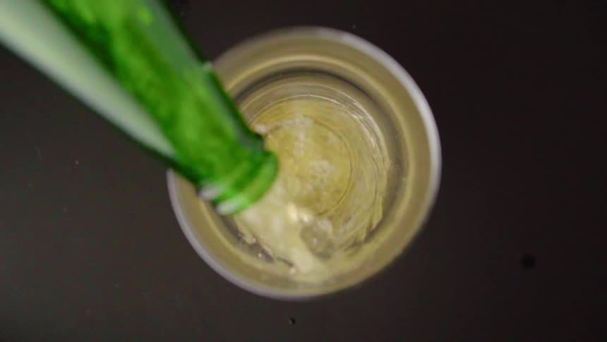 A drink is being poured into the glass from a bottle