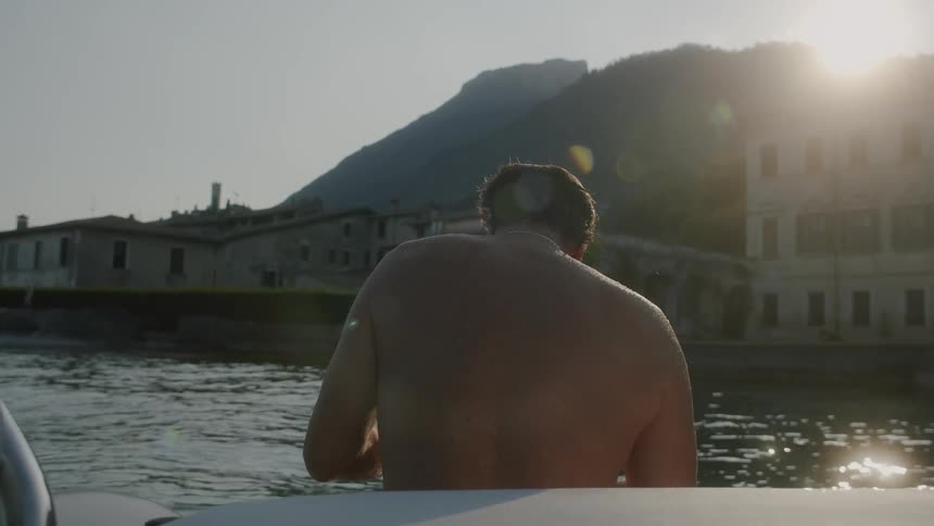 A shirtless man sit near river