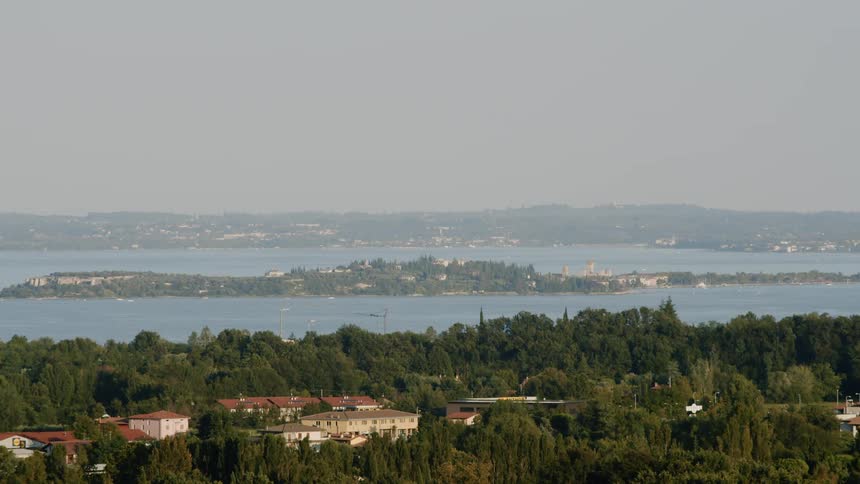 An ocean harbor with trees and homes on shore on a hazy day