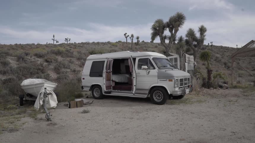 A van sits with its doors wide open and a boat is parked beside it