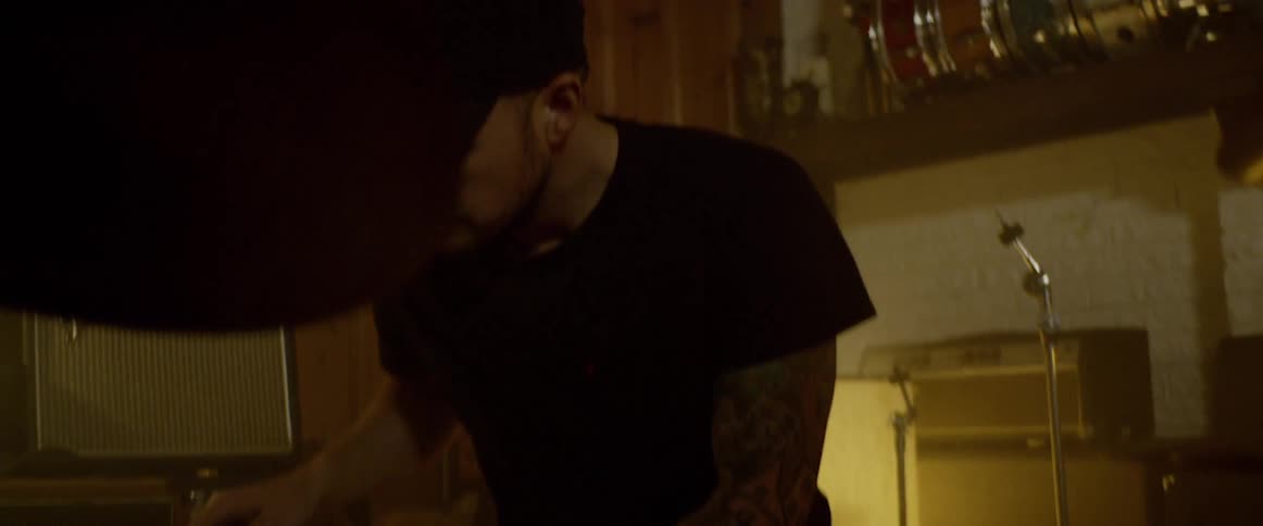 A drummer plays in a lowly lit studio