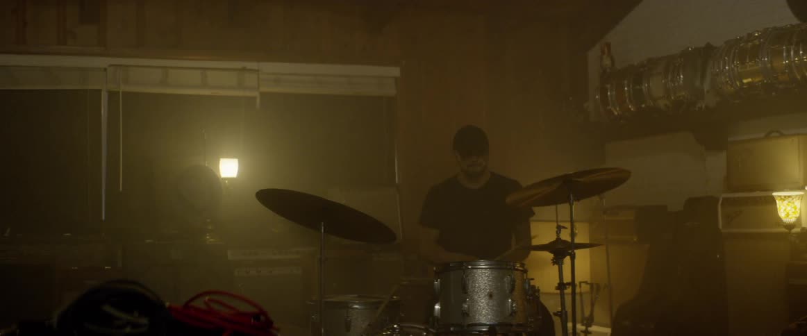 Man sitting in front of drum set inside studio