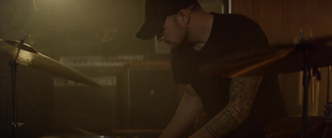 A drummer plays in a lowly lit studio
