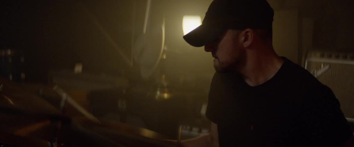 A drummer plays in a lowly lit studio