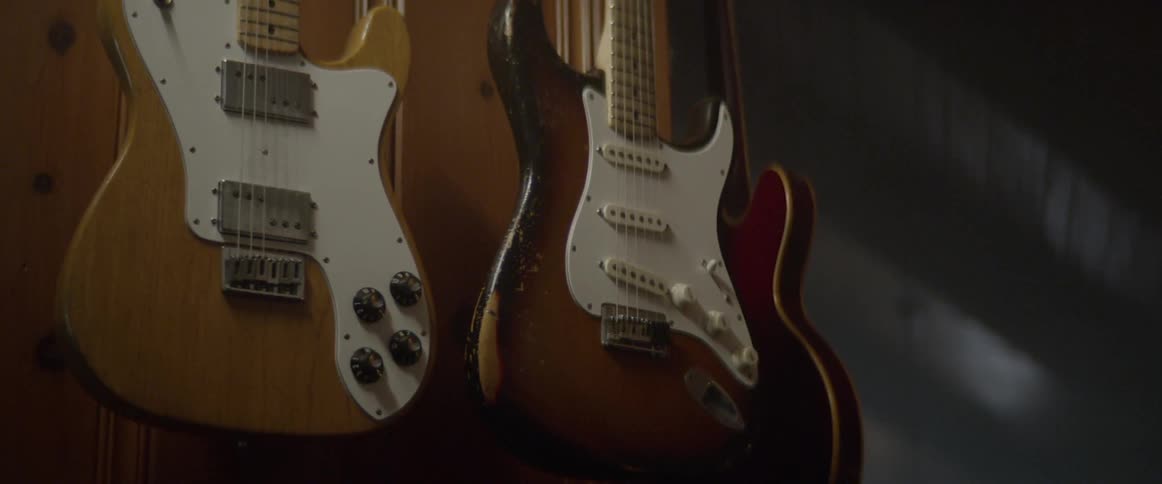 A telecaster stratocaster and gibson hang on a wall