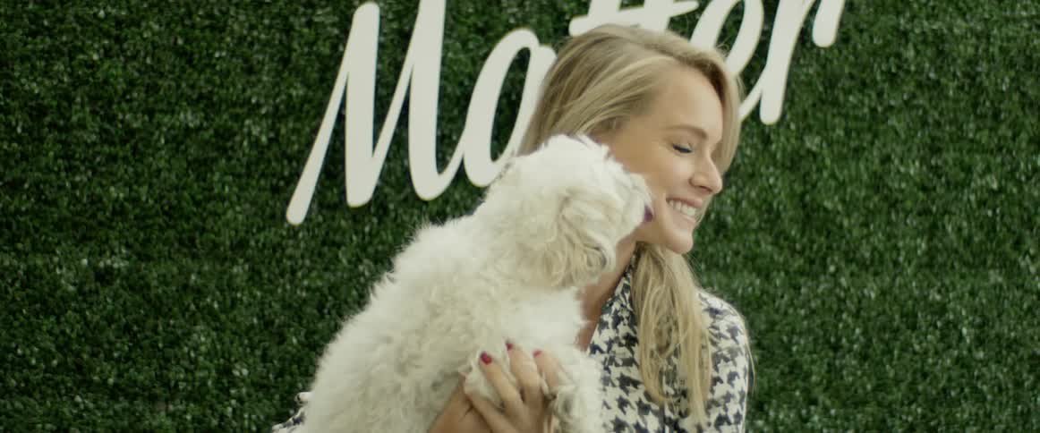 A woman holding a dog in front of plants