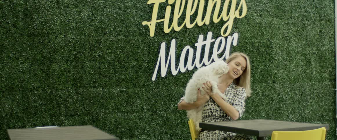 A white woman plays with a small white dog
