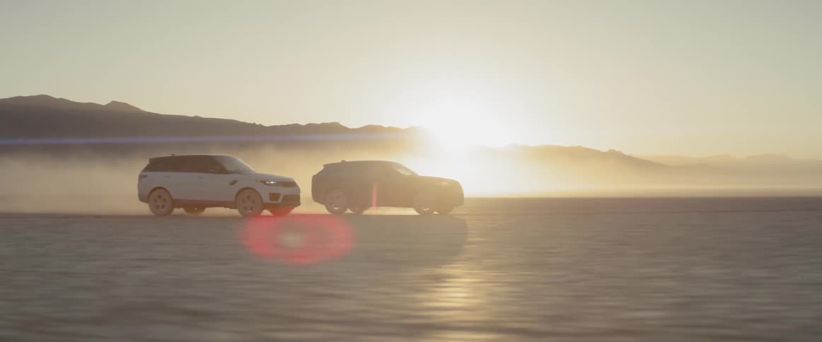 Two range rover sports race across the salt flats at sundown