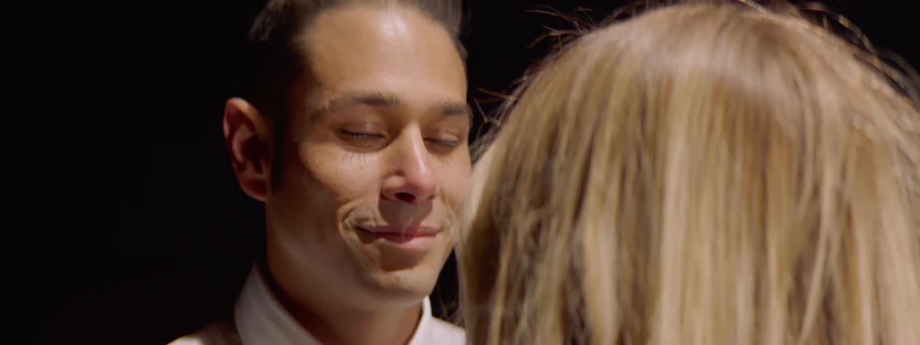 A man and woman gaze at each other as they slowly dance
