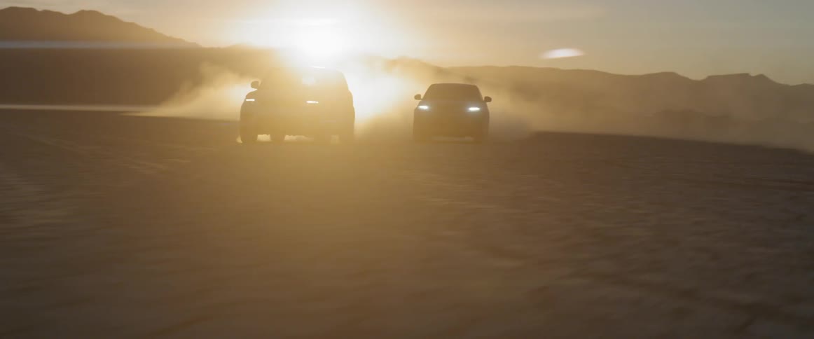 Two cars are driving with their headlights on as the sun sets