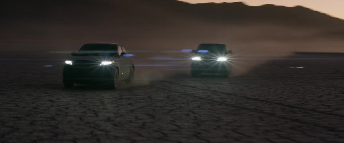 Vehicles are driving in a desert area at dusk