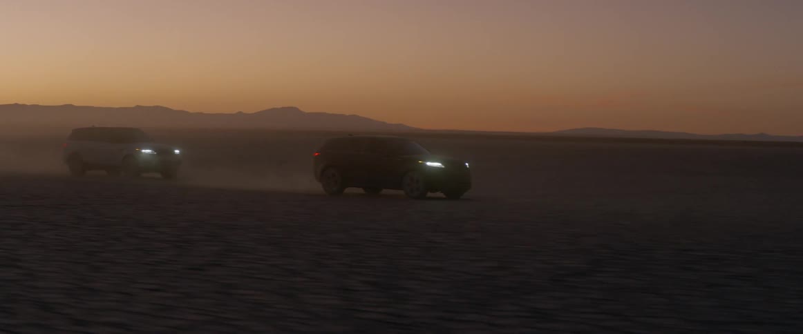 A black range rover sport driving across the salt flats at sunset