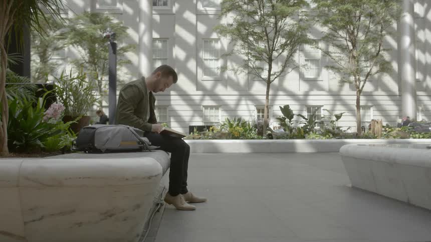 Man sits outdoors and writes in a notebook