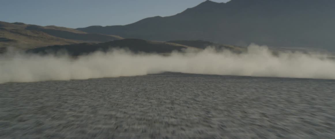 The vehicles race in the desert causing dust clouds