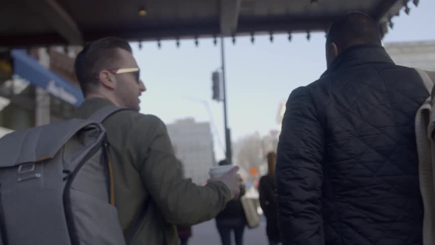 Two men walk and talk in the city