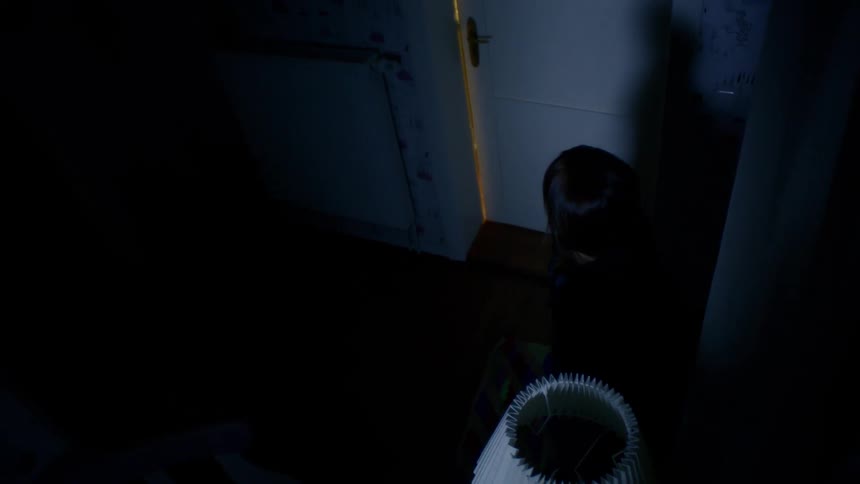 A woman walks into a dark hallway and struggles to turn on a lamp