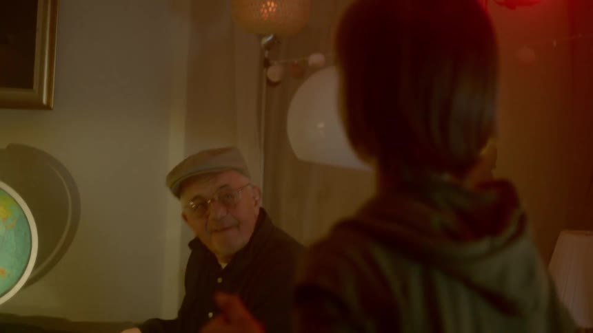 An elderly man plays a piano while a young boy dances