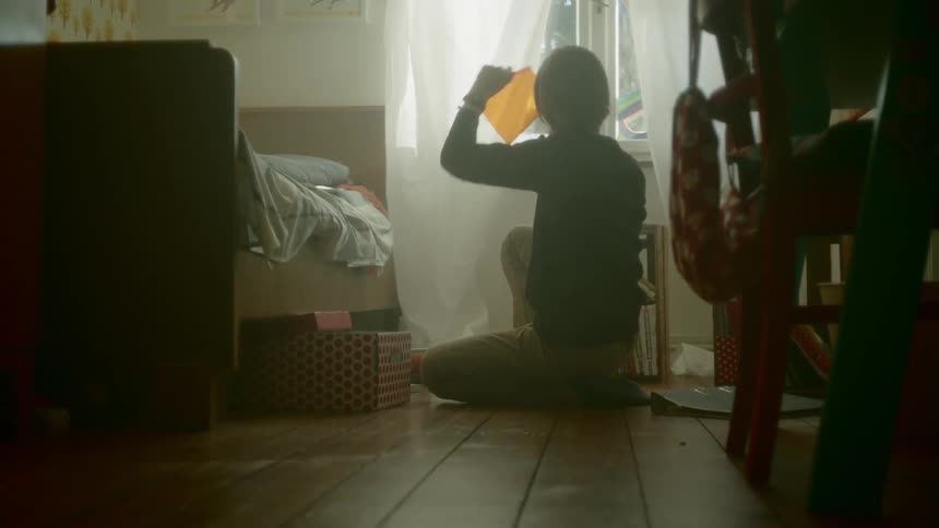 A kid pulls things out from inside a box that was under her bed
