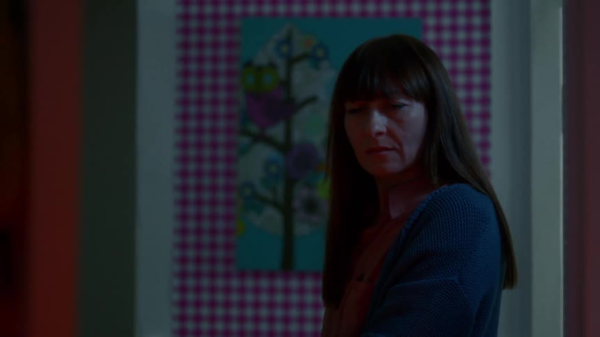 A woman passes by an open doorway and pauses momentarily as if she is confused by something she sees