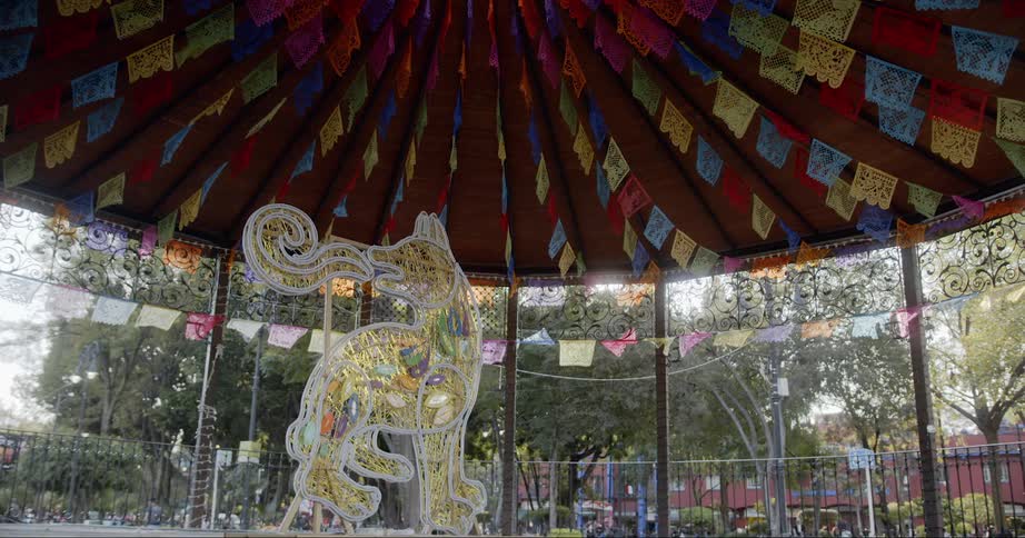 A gazebo in the middle of a park with people and buildings in the background