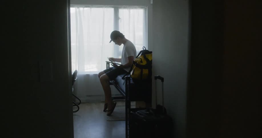 A young man sits in a room while going through a folder