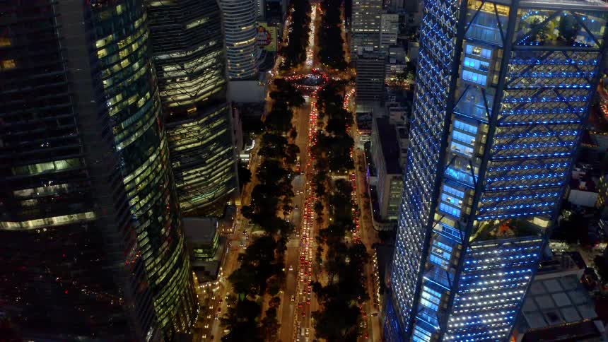 A large city has several towering skyscraper and one that can change its lights to create an impressive display of cascading numbers