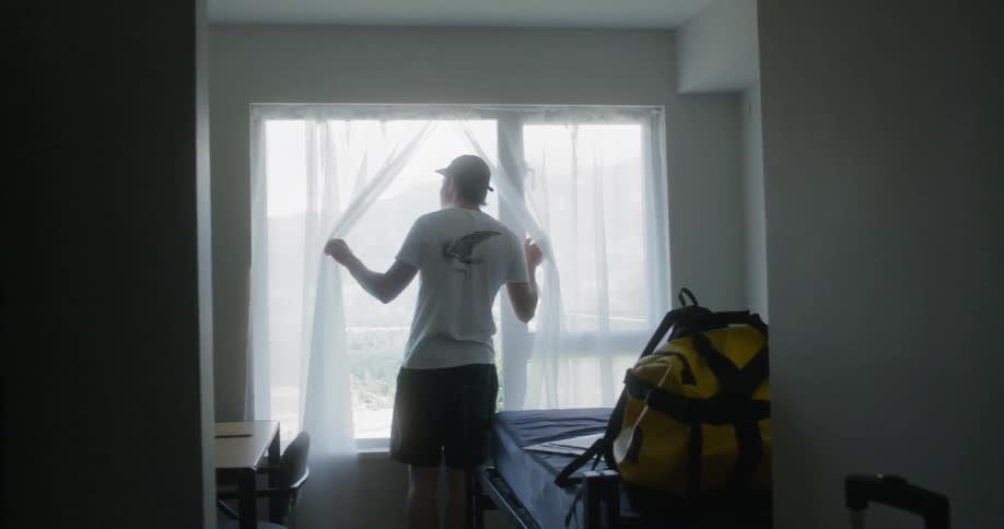 The man walks to the window to look out