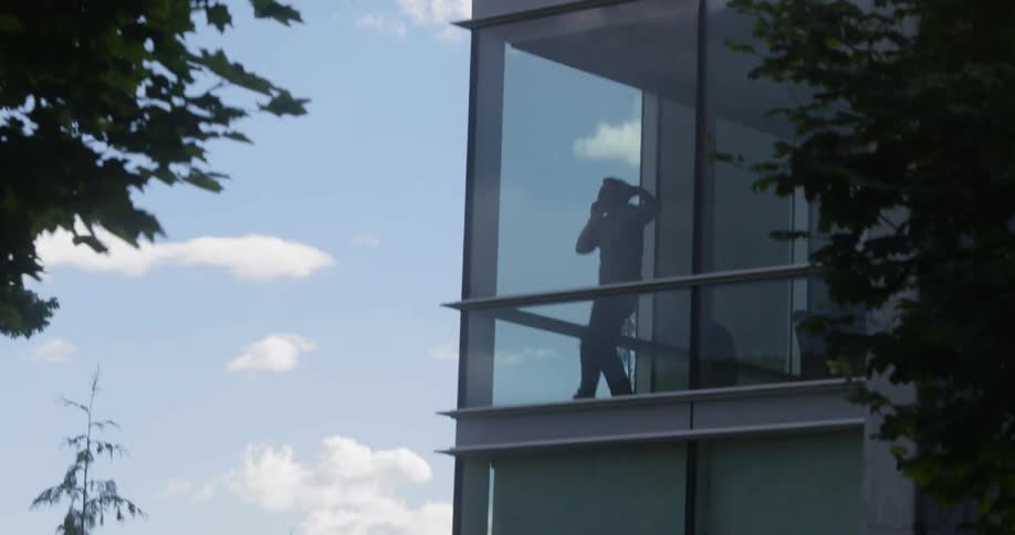 A man in an office building talks on the phone and slams his fists and yells