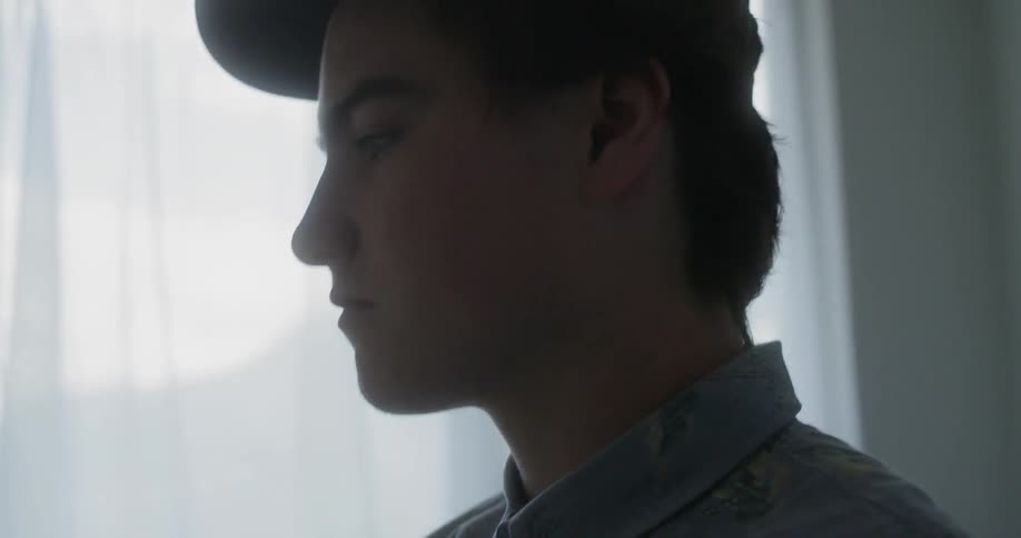 A boy takes his headphones off and smooths his hair back over his ears