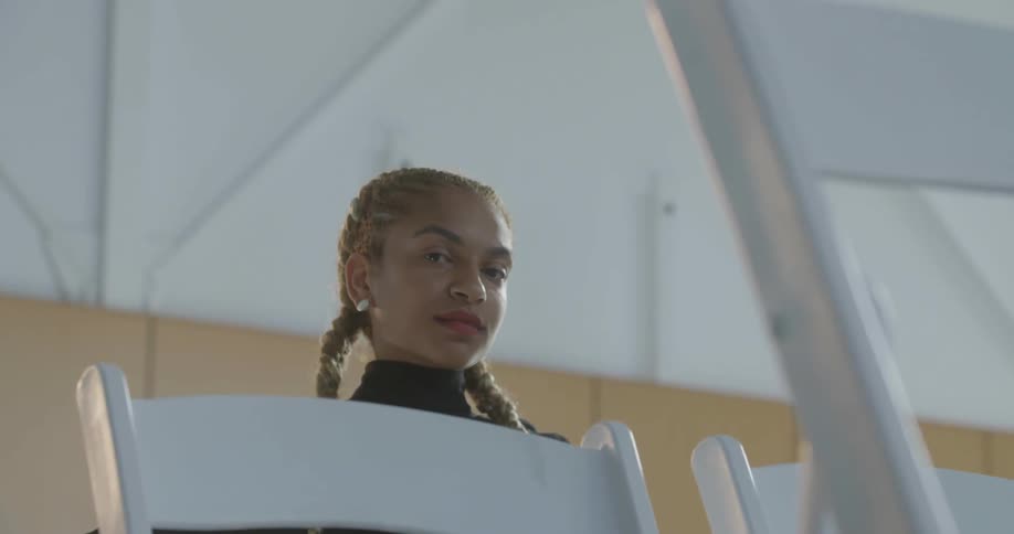 Woman looks down past white chairs