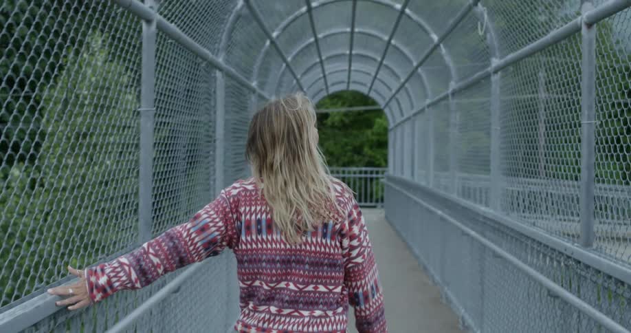 A woman in a red and white sweater walking on a pathway with trees in the background